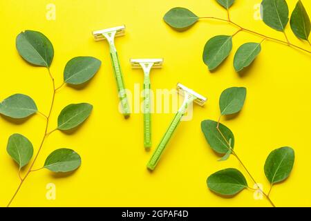 Safety razors and eucalyptus branches on yellow background Stock Photo