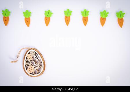 Easter pattern made with carrots and a cute Easter egg decoration on white background. Creative minimal holiday flat lay concept. Spring holidays conc Stock Photo