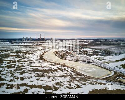 Aerial view of power station in evening light. Early spring urban industrial landscape. Snow melting, Season change. Gas power plant near big city Min Stock Photo