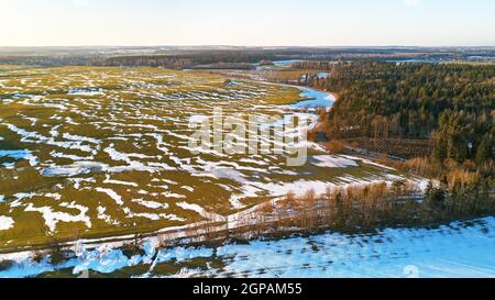 Spring fields aerial view. Snow melting, water pools on meadows. Season change. March rural landscape. Winter crops and plowed field panorama. Belarus Stock Photo