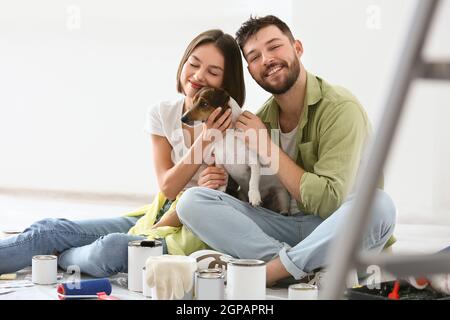 Young couple with cute dog resting during repair of their new house Stock Photo