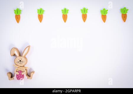 Easter pattern made with carrots and a cute Easter bunny on white background. Creative minimal holiday flat lay concept. Spring holidays concept. Top Stock Photo