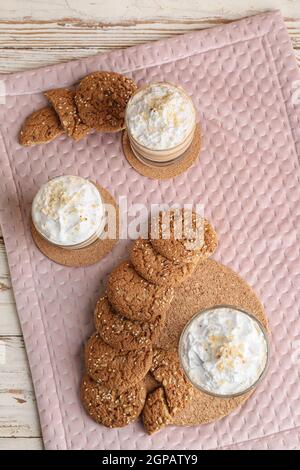 Glasses of tasty latte with nuts and cookies on white wooden background Stock Photo