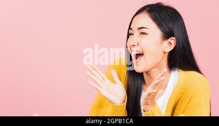 Happy Asian portrait beautiful cute young woman standing surprised excited screaming open mouth show hand studio shot isolated on pink background, Tha Stock Photo