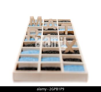 Low angle view on a wooden box of square compartments rectangular compartments filled with blue or black decorative sand as well as the letters M, A, Stock Photo