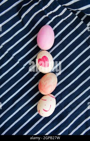 Beautiful Easter eggs painted with watercolors lie on a striped blue fabric. Easter holiday concept Stock Photo