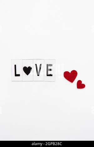 Beautiful inscription love on a white background, small red hearts. Postcard Stock Photo