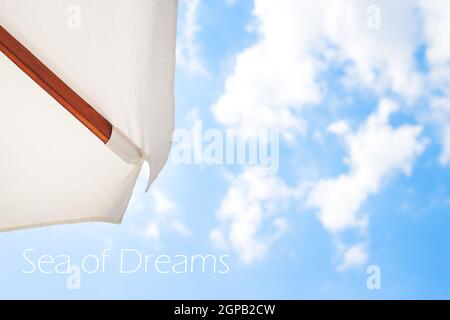 White umbrella-view from above on a beautiful blue sky, inscription in dreams of the sea. Stock Photo