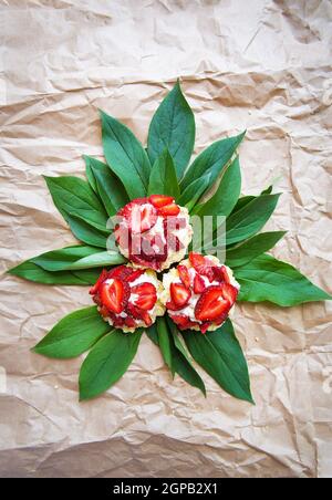 Beautiful and bright cupcakes with strawberries lie on green leaves. Stock Photo