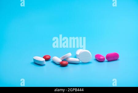 White and pink tablets pills on blue background. Pharmacy banner. Pharmaceutical industry. Health insurance strategy. Pharmaceutical manufacturing. Ta Stock Photo