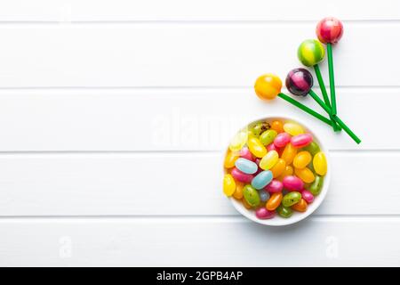 Sweet fruity lollipops and jelly beans on white table. Top view. Stock Photo