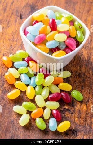 Sweet colorful jelly beans in bowl on wooden table. Stock Photo