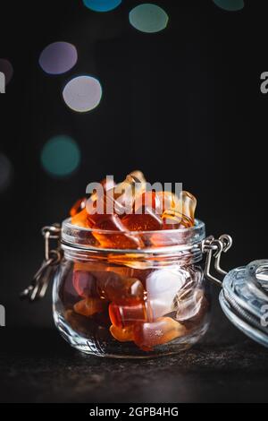 Jelly candies with cola flavor in jar on black table. Stock Photo