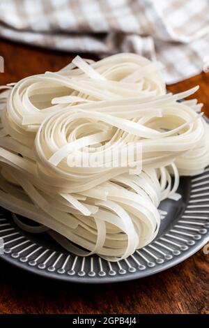 Dried white rice noodles. Raw pasta. Uncooked noodles on plate. Stock Photo
