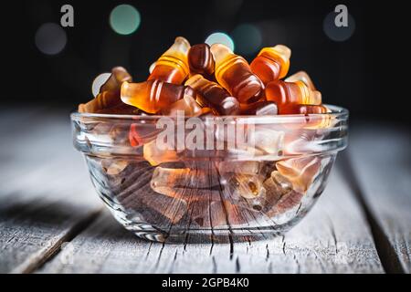 Jelly candies with cola flavor in bowl on black table. Stock Photo