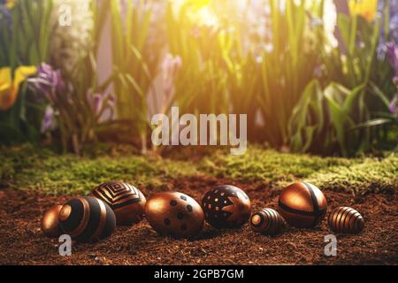 Easter golden and black eggs with geometric pattern, spring flowers on background Stock Photo