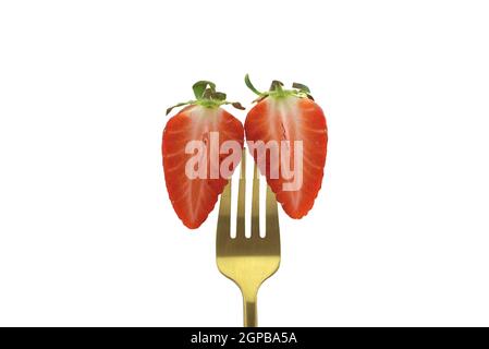 Two halves of a half-cut strawberry pinned on a golden fork isolated on a white background Stock Photo