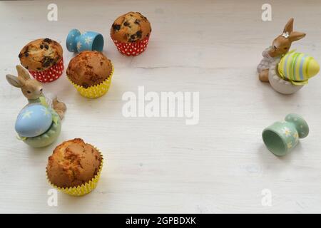Easter table with muffins, colored eggs and bunnies. Copy space, white table Stock Photo