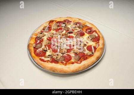 Delicious tomato sauce cheese covered hot and tasty Pepperoni Sausage Mushroom Onion pizza pie Stock Photo
