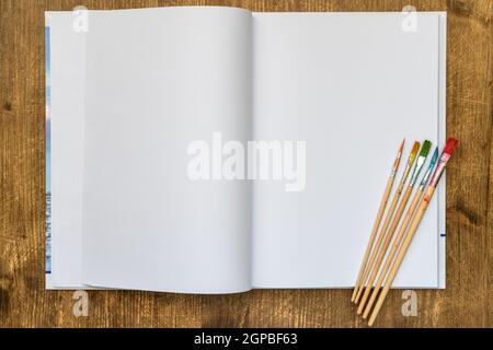 White blank pages sketchbook with paintbrushes on wood table Stock Photo