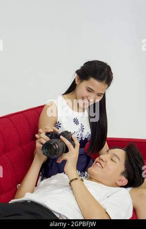 Young lovers spend time together on holidays in the photo studio. The young man allow her girlfriend to view pictures taken on the camera screen while Stock Photo