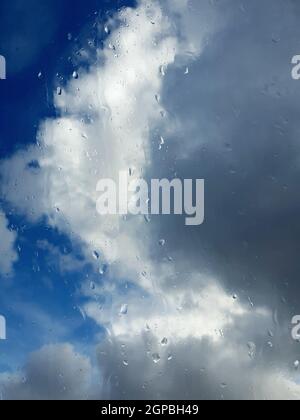 Raindrops on the window during stormy and rainy weather. View of dark clouds behind the window. Stock Photo