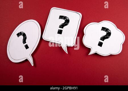 Three speech bubbles with question marks on a red background. Stock Photo
