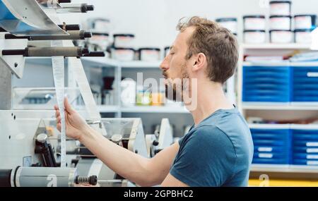 Man checking quality of labels in printing shop carefully Stock Photo
