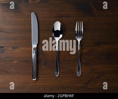 A spoon, fork and knife on a wooden table. View from above. Stock Photo