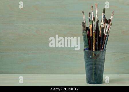 Assorted dirty painting brushes in plastic flask Stock Photo