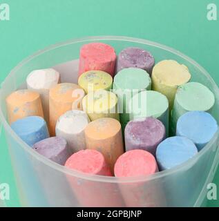 multicolored chalk in a plastic bucket on a green background, close up Stock Photo