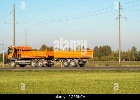 Orange dump truck goes on country highway Stock Photo