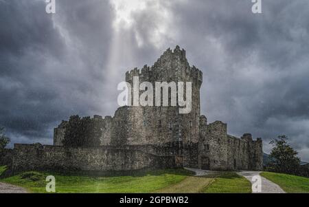Ross Castle under very heavy lashing rain and thunderstorm with dramatic clouds, located on the bank of Lough Leane, Ring of Kerry, Killarney, Ireland Stock Photo