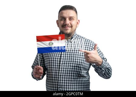 White guy holding a flag of Paraguay and points the finger of the other hand at the flag isolated on a white background. Stock Photo