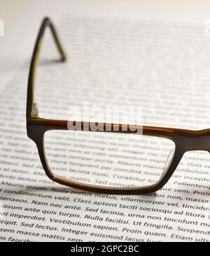 Closeup of eyeglasses on paper sheet with lorem ipsum text. Stock Photo