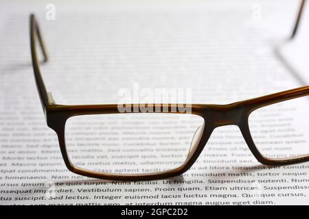 Closeup of eyeglasses on paper sheet with lorem ipsum text. Stock Photo