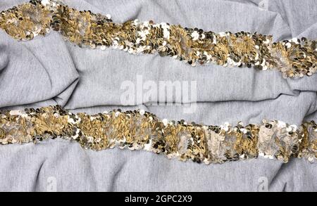 gray cotton fabric with golden round sequins, full frame Stock Photo
