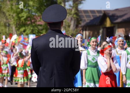 Slavyansk-on-Kuban, Russia - May 1, 2018: A policeman, who cries out the tranquility of citizens at a festive procession. Celebrating the first of May Stock Photo