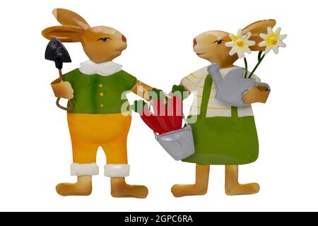Easter decoration element. Close-up of two bunnies with garden tools and flowers isolated on a white background.  Handmade and then painted. Macro. Stock Photo