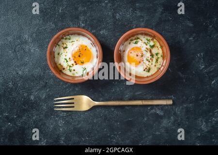 Two fried eggs in a round ceramic dish in the form of eyes. Cooked small fried eggs is a simple breakfast. Top view, close up Stock Photo
