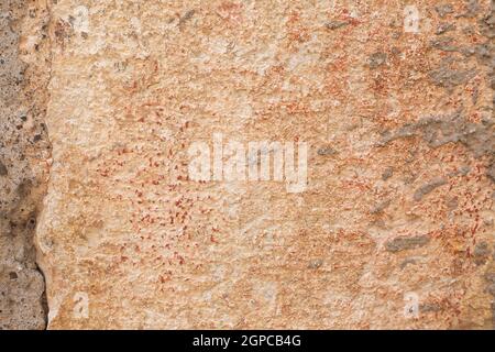 Beige and orange big stone block of wall with cement and red paint dots. Background and wallpaper textured picture. Copy space. Natural construction Stock Photo