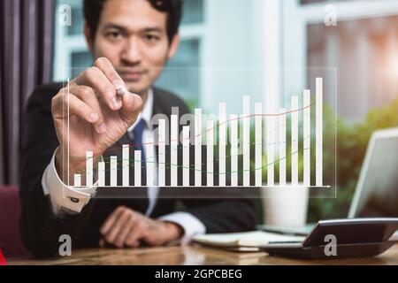Business man holding pen drawing graph finance on virtual screen in his office Stock Photo