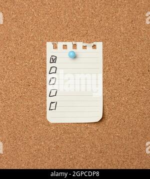 blank sheet of paper in a line attached with a plastic button on a brown cork board, copy space Stock Photo