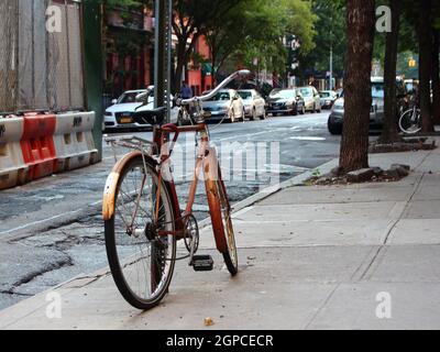 Single Worn Bike Locked and Parked Leaning on Pole Stock Photo