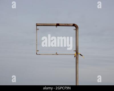 An empty sign frame, possibly a road sign or a traffic sign. The sign itself is missing, and there is a piece of yellow and black plastic tied around Stock Photo