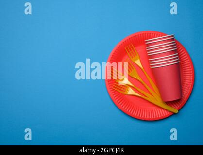orange plastic forks and empty red paper disposable plates on a blue background, top view, set Stock Photo