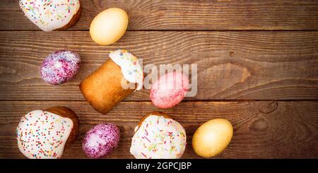 Easter cakes and Easter colored eggs on a wooden background. Religious holiday of bright Easter. Stock Photo