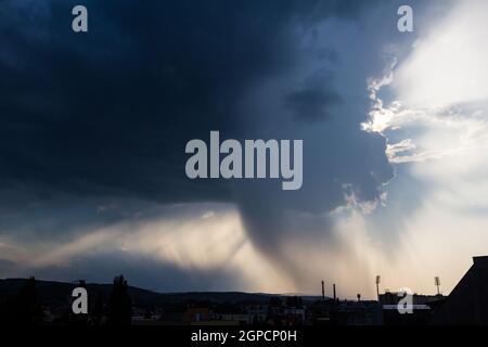 Dramatic storm clouds with sun shining from behind over the city, Sopron, Hungary Stock Photo