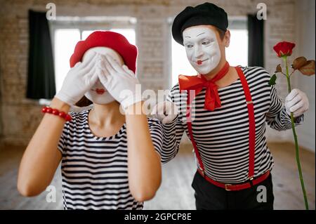 Two mime artists, surprise with rose scene, parody comedy. Pantomime theater, comedian, positive emotion, humour performance, funny face mimic and gri Stock Photo