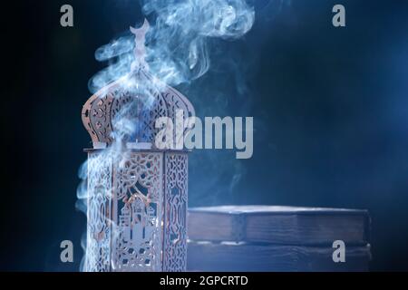 Ornamental Arabic lantern with with Holy Quran. Festive greeting card for Muslim holy month Ramadan Kareem. Stock Photo